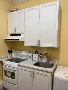 a small kitchen with white cabinets and a sink at Entire Guest Suite - 1 bedroom w/ Private Entrance in Surrey