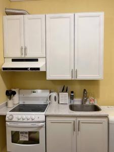 a kitchen with white cabinets and a stove and a sink at Entire Guest Suite - 1 bedroom w/ Private Entrance in Surrey