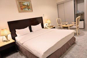 Al Furat Madayin Hotel في الرياض: غرفة نوم بسرير كبير وطاولة وكراسي