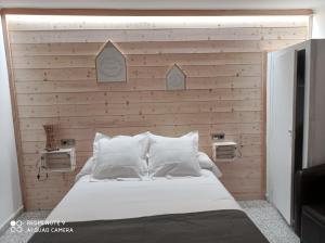 1 dormitorio con cama blanca y pared de madera en Casa Rural Felip, en Espot