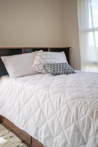 Una cama con sábanas blancas y almohadas. en Skyline Suites Grenada en Grand Anse