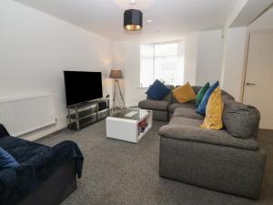 a living room with two couches and a flat screen tv at 1 Dulas Apartments in Abergele