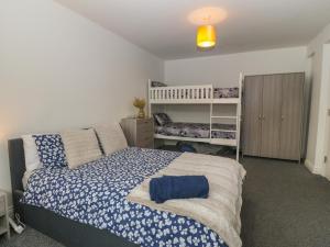a bedroom with a large bed with blue and white sheets at 1 Dulas Apartments in Abergele