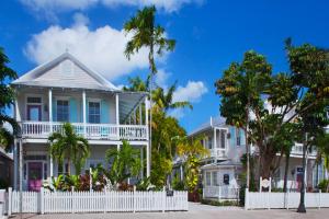 uma casa com uma cerca branca em frente a palmeiras em Coco Plum Inn em Key West