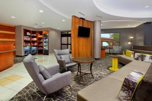 a lobby with a waiting area with chairs and a tv at SpringHill Suites Phoenix Glendale Sports & Entertainment District in Glendale