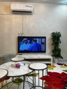 Holiday apartment في مكة المكرمة: غرفة معيشة مع تلفزيون وطاولتين وكراسي