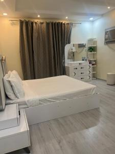 a bedroom with a white bed and a dresser at Holiday apartment in Makkah