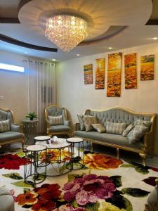 una sala de estar con sofás, mesas y una lámpara de araña. en Holiday apartment, en La Meca