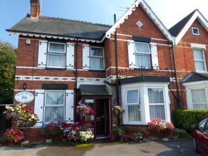 una casa de ladrillo rojo con flores delante en South Rising Guest House, en Poole