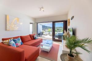 Green View at Blue Bay Golf & Beach Resort في Dorp Sint Michiel: غرفة معيشة مع أريكة حمراء وطاولة