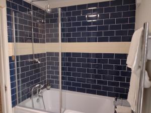 a blue tiled bathroom with a tub and a shower at 2 Courtyard Mews in Penzance +15 photos