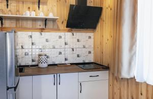 a small kitchen with white cabinets and a refrigerator at Villa Machakhela●ვილა მაჭახელა in Batumi