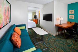 um quarto de hotel com um sofá, uma cama e uma secretária em SpringHill Suites by Marriott Orlando Lake Buena Vista in Marriott Village em Orlando