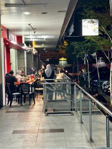 un grupo de personas sentadas en mesas en un restaurante en Sweet Studio Apartment, en Kota Bharu