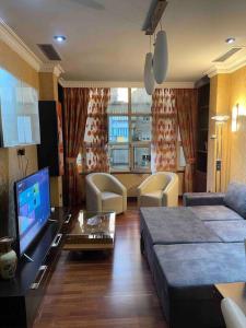 een woonkamer met een bank en een tv bij Edjon Apartments in Tirana