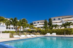 - une piscine en face d'un bâtiment avec des palmiers dans l'établissement Green View at Blue Bay Golf & Beach Resort, à Dorp Sint Michiel