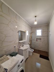 uma casa de banho branca com um lavatório e um WC em Casa de langa lac em Oradea