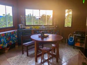 eine Küche mit einem Holztisch, Stühlen und Fenstern in der Unterkunft Espaço Ajna in Alto Paraíso de Goiás + 5 Fotos