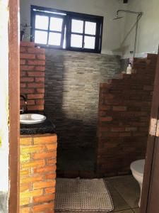 ein Badezimmer mit einer Ziegelwand und einem Waschbecken in der Unterkunft Espaço Ajna in Alto Paraíso de Goiás