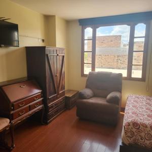 sala de estar con silla, cómoda y ventana en Hotel Bella Casona, en Riobamba