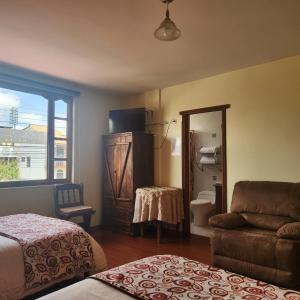 a bedroom with a bed and a couch and a mirror at Hotel Bella Casona in Riobamba