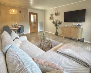 ein Wohnzimmer mit einem Sofa und einem Flachbild-TV in der Unterkunft Ferienwohnung Tiefenbach mit Garten in Oberstdorf