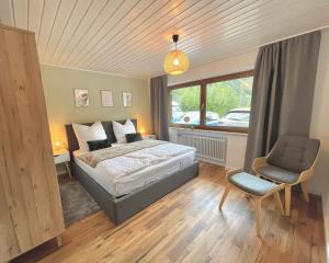 a bedroom with a bed and a chair and a window at Ferienwohnung Tiefenbach mit Garten in Oberstdorf