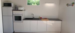 a white kitchen with a sink and a refrigerator at Soley Bungalows Carambole 2 pers Adult only in Sainte-Anne