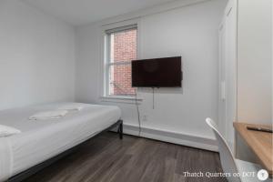 a bedroom with a bed and a flat screen tv at Quarters on DOT by Thatch in Boston