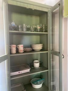 a glass cabinet with dishes and bowls and plates at Residencial Vila Suel in Praia do Rosa