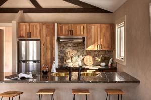 cocina con armarios de madera y encimera de granito en Lodge Chalet 28 - The Stables Perisher en Perisher Valley