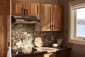 a kitchen with wooden cabinets and a stone wall at Lodge Chalet 28 - The Stables Perisher in Perisher Valley