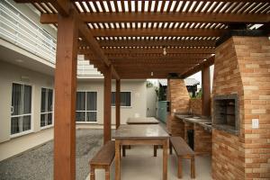 un patio con una pérgola de madera y una mesa en 3- AKAHAI -Aloha Bratz Apartments, en Palhoça