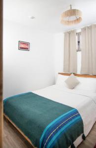 1 dormitorio con 1 cama blanca grande con manta verde en Oceana Surf Camp, en Taghazout