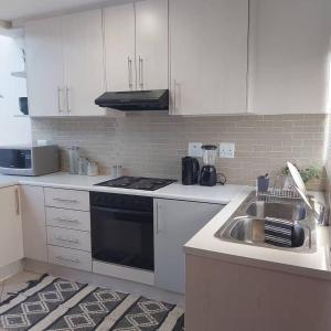 une cuisine blanche avec un évier et une cuisinière dans l'établissement Cozy Stay, à Windhoek