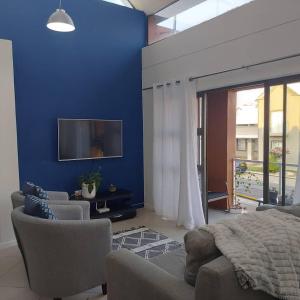 - une chambre dotée d'un mur bleu avec un lit et des chaises dans l'établissement Cozy Stay, à Windhoek 9 autres photos