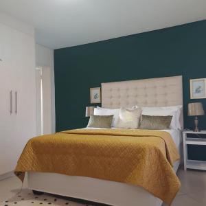 une chambre avec un grand lit avec un mur bleu dans l'établissement Cozy Stay, à Windhoek