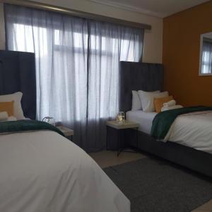 a bedroom with two beds and a window with curtains at Cozy Stay in Windhoek