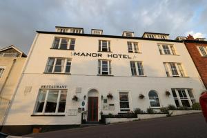 - un bâtiment blanc avec l'hôtel manoir écrit sur celui-ci dans l'établissement Manor Hotel, à Exmouth