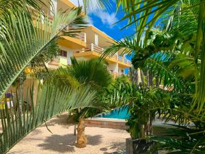 a resort with palm trees in front of a building at Isla penthouse & garden apartments Bonaire in Kralendijk