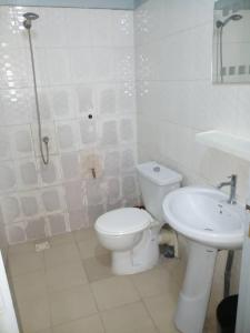 La salle de bains blanche est pourvue de toilettes et d'un lavabo. dans l'établissement KEUR AMINATA, à Dakar