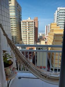 eine Hängematte auf einem Balkon mit Stadtblick in der Unterkunft Apartamento a 50 metros da Praia para utilização da piscina precisa de Atestado Médico in Praia Grande