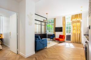 ein Wohnzimmer mit einem blauen Sofa und orangefarbenen Stühlen in der Unterkunft Amazing appartement - 8P - Le Bon Marché in Paris