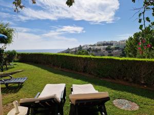 two chairs and tables on a lawn with a view of the ocean at Amazing Studio with Ocean View, Pool and Beach in Lagos