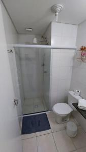 ein weißes Bad mit einer Dusche und einem WC in der Unterkunft Apartamento a 50 metros da Praia para utilização da piscina precisa de Atestado Médico in Praia Grande