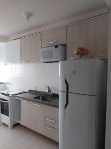 eine Küche mit einem weißen Kühlschrank und einer Spüle in der Unterkunft Apartamento a 50 metros da Praia para utilização da piscina precisa de Atestado Médico in Praia Grande