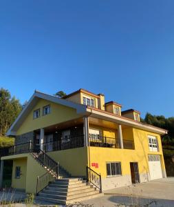 um edifício amarelo com escadas em frente em Casa SobreMonte em Muxía