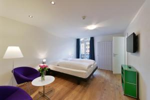 a bedroom with a bed and a table and purple chairs at Hotel Sternen in Lenk