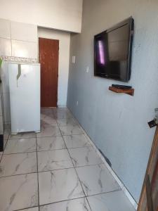 Cette chambre dispose d'un réfrigérateur et d'une télévision murale. dans l'établissement Linda kitinet, à Cabo Frio