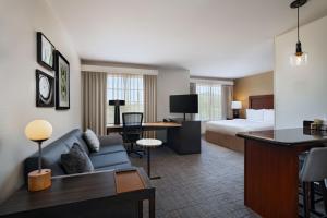 a hotel room with a couch and a bed and a desk at Residence Inn Beaumont in Beaumont